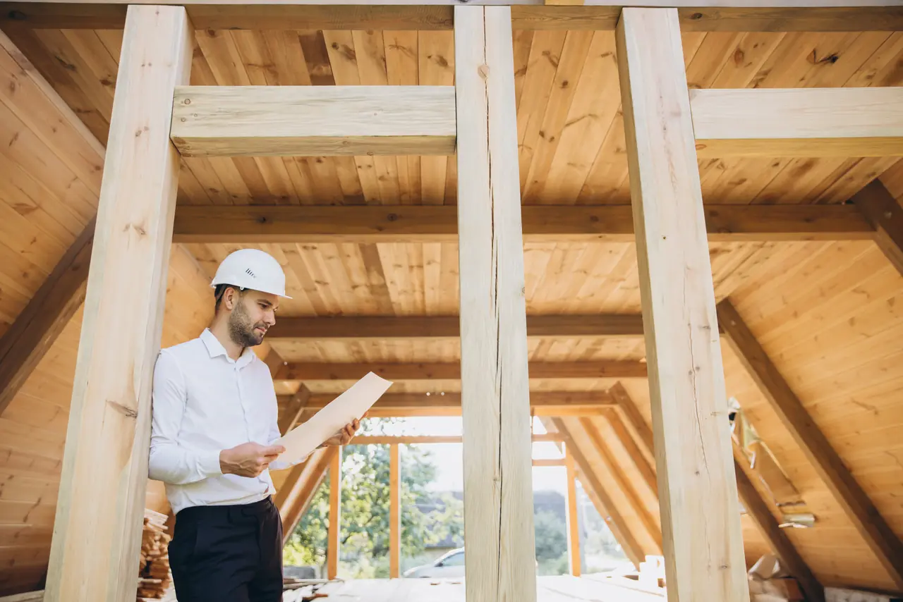 Person reviewing plans inside a timber house frame